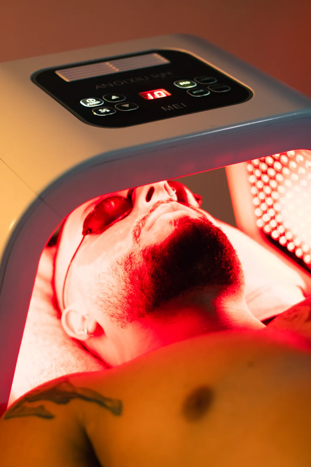 Man relaxing beneath a red light therapy lamp